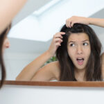 Girl looking at her scalp in the mirror