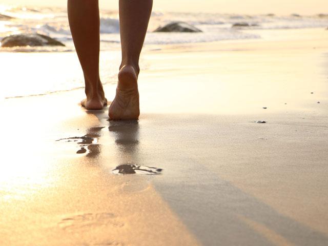 Person walking barefoot on the beach on the shoreline