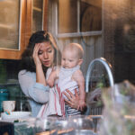 tired mother with baby in a messy kitchen
